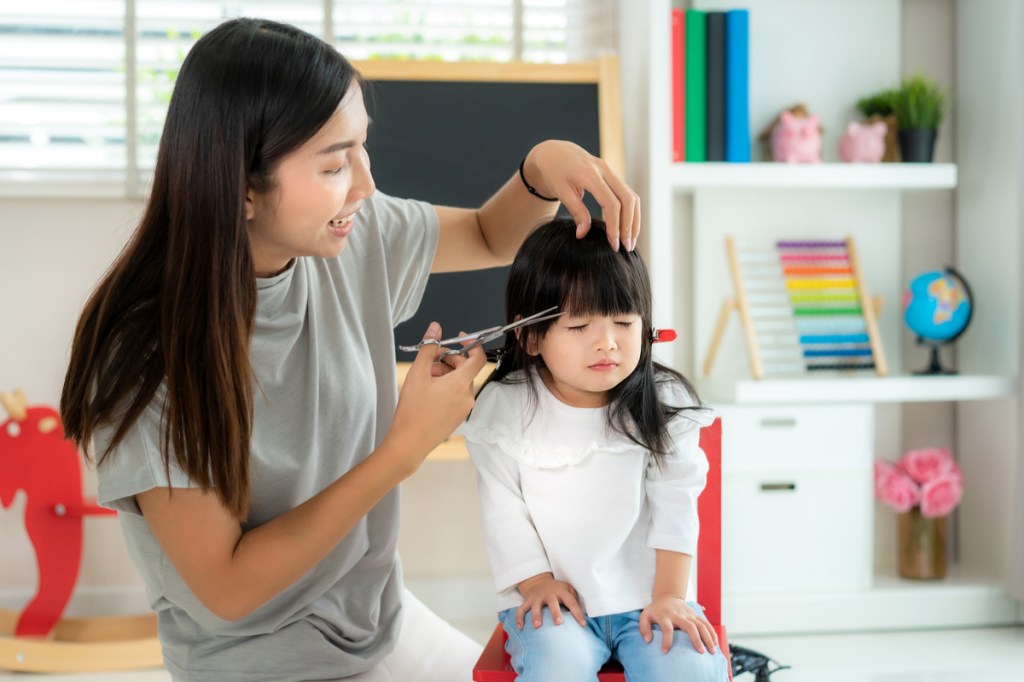 A mother giving her daughter an at home haircut.