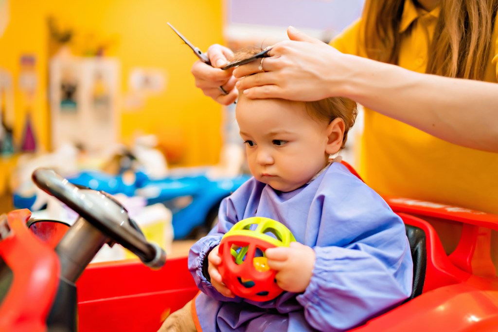 A child getting a haircut in a salon chair.