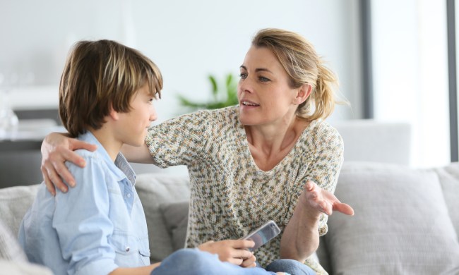 A mother talking to her teenage son while sitting on the couch.