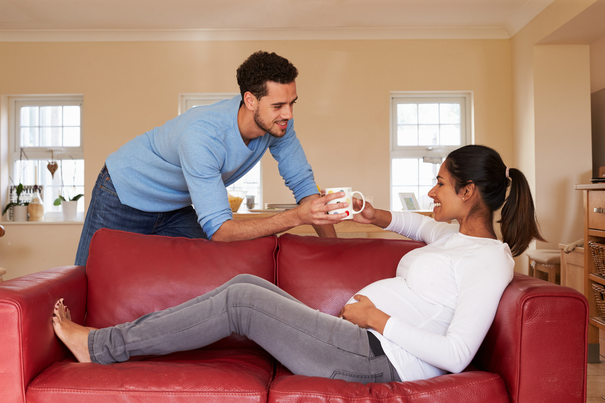 A man handing a pregnant person a hot drink