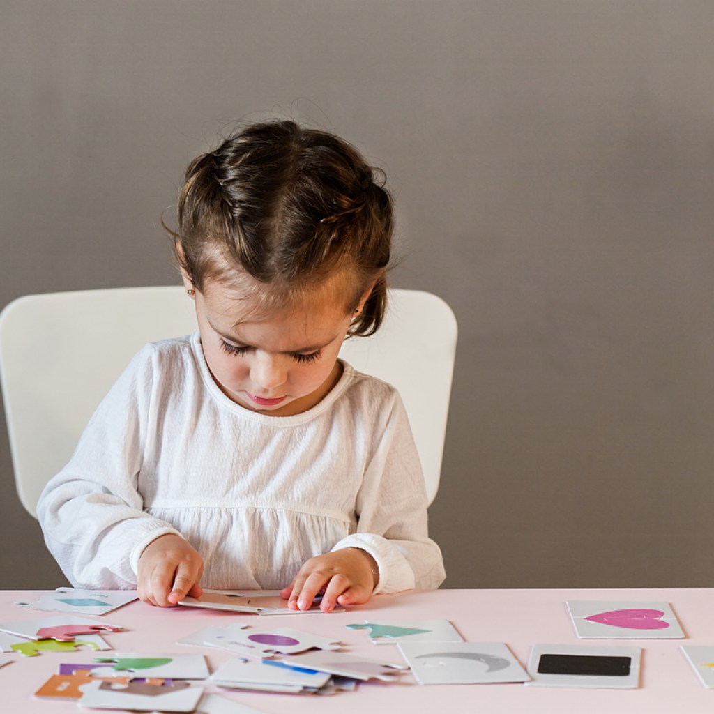 A little girl playing a card game by herself.