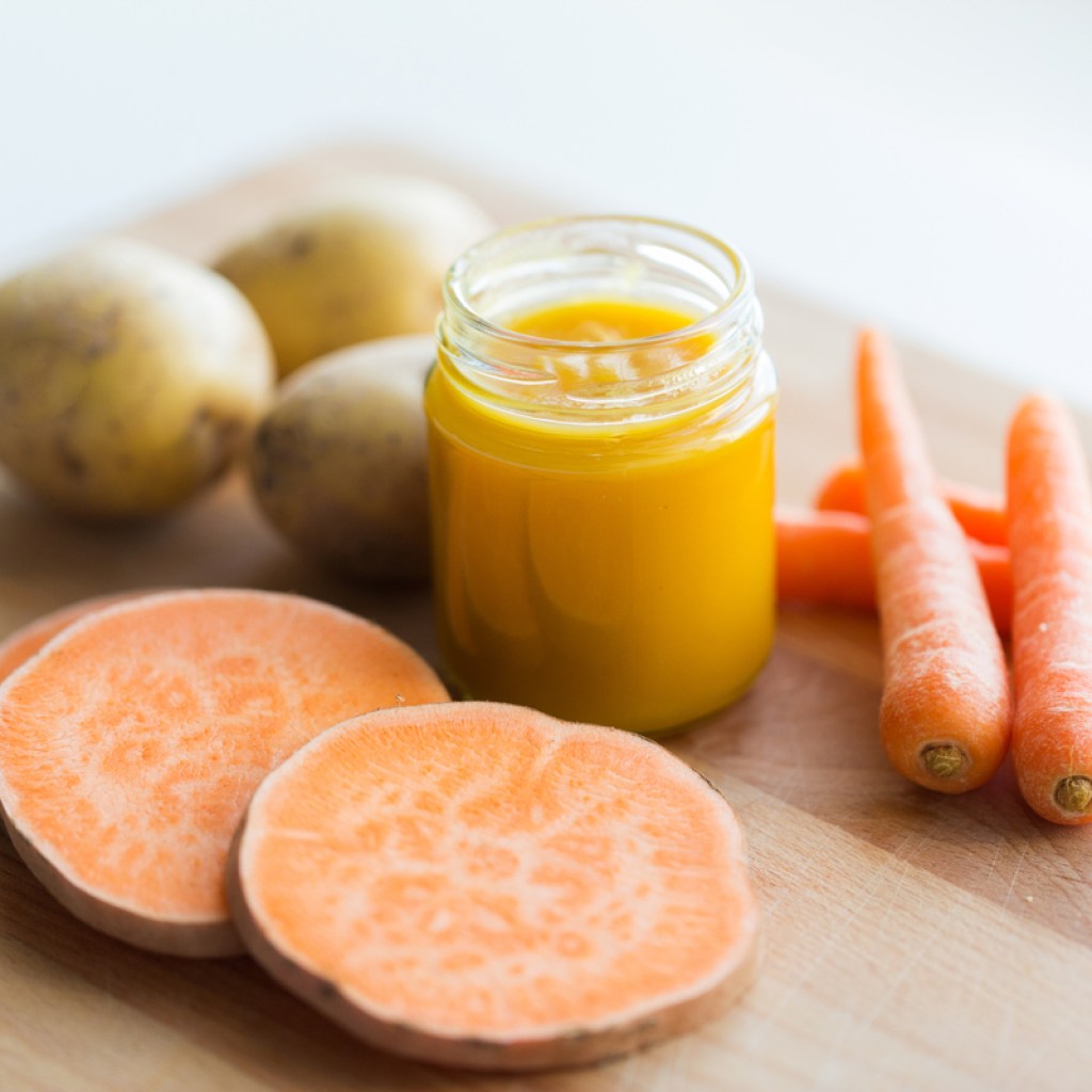 Sweet potatoes, carrots, regular potatoes, and baby food on a table.