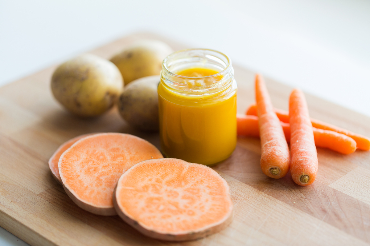 Sweet potatoes, carrots, regular potatoes, and baby food on a table.