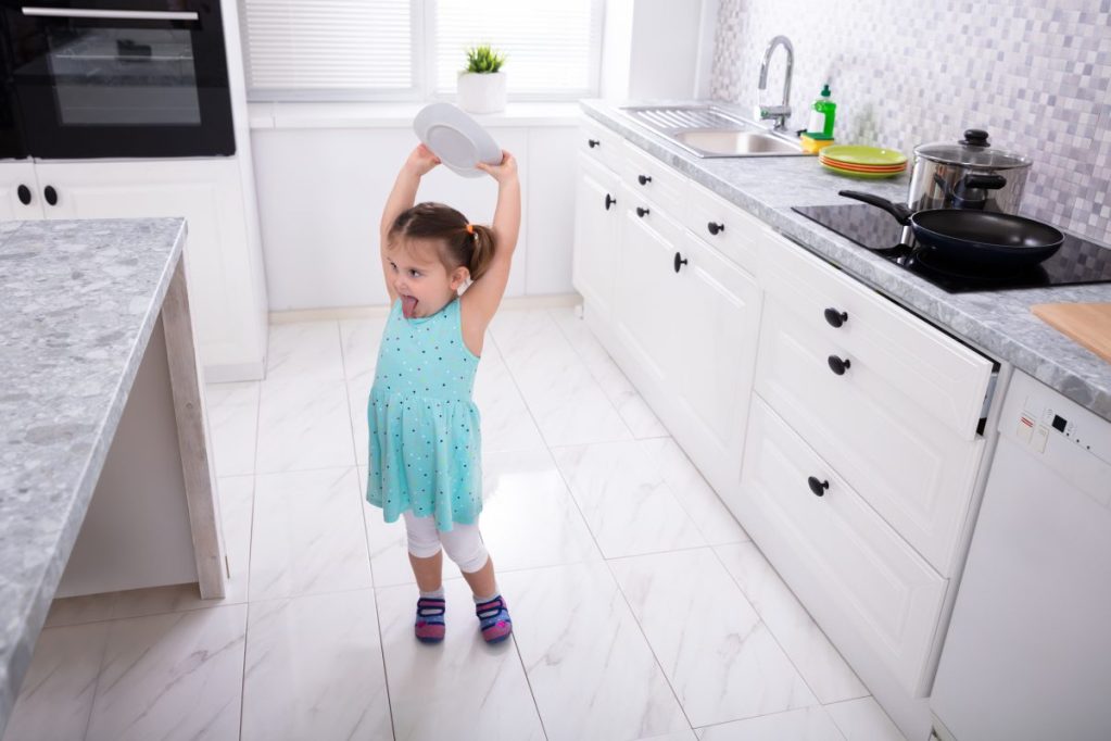 Little girl about to throw a bowl on the kitchen floor.