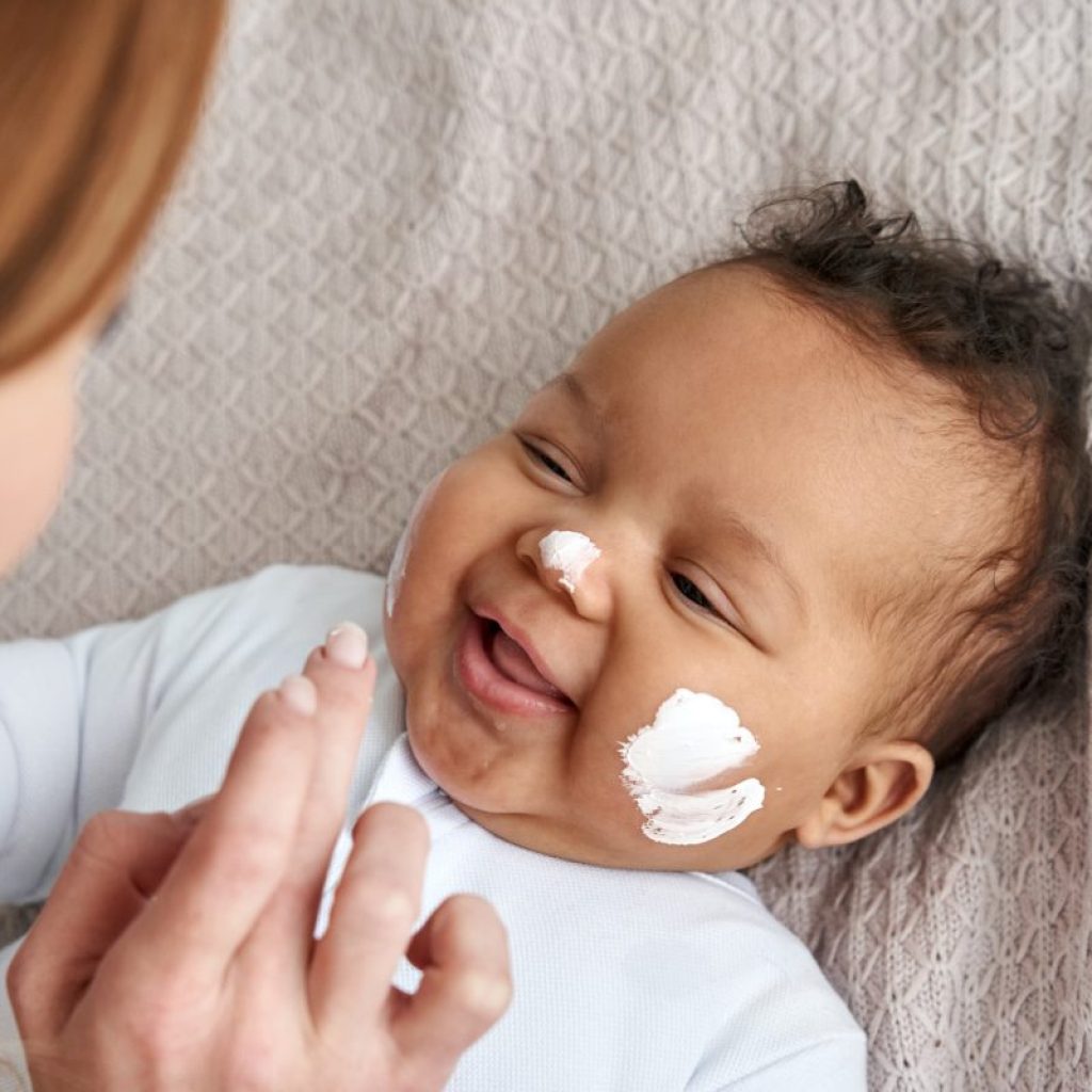A parent putting sunscreen on a baby's face.