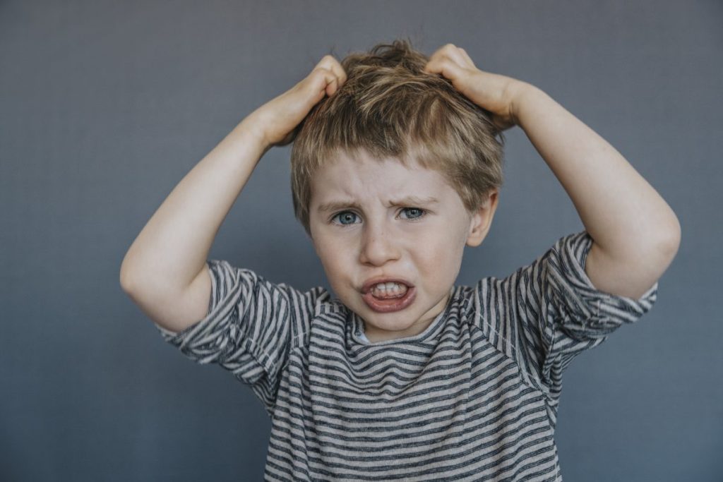 A little upset boy pulling at his hair.