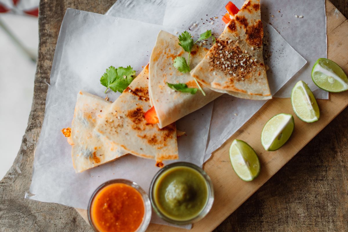 Quesadillas beside tray of dips and lime slices