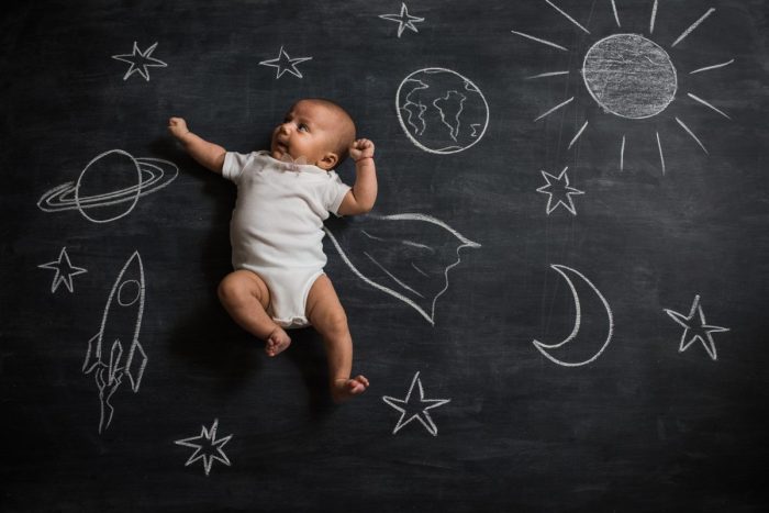 A baby laying on a chalk drawing of outer space