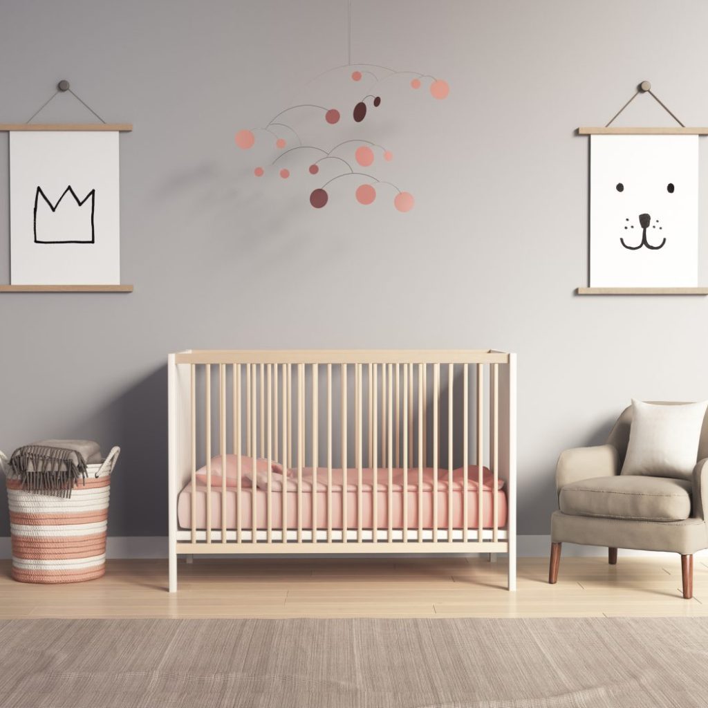 A baby nursery with a crib, chair, wall hangings, and laundry basket