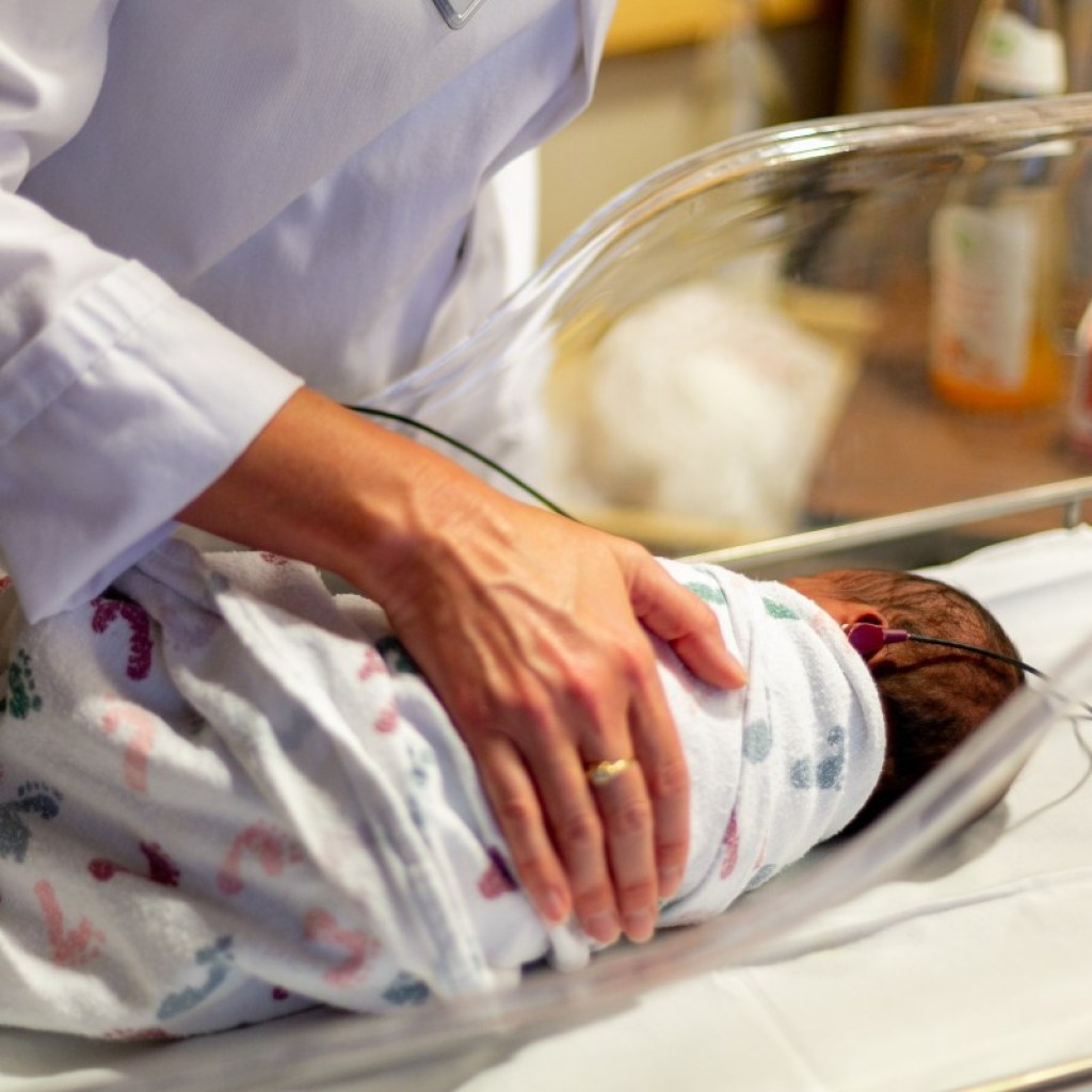 A doctor with a baby in a hospital bassinet