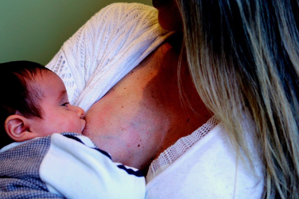 a woman in a white top breastfeeding an infant