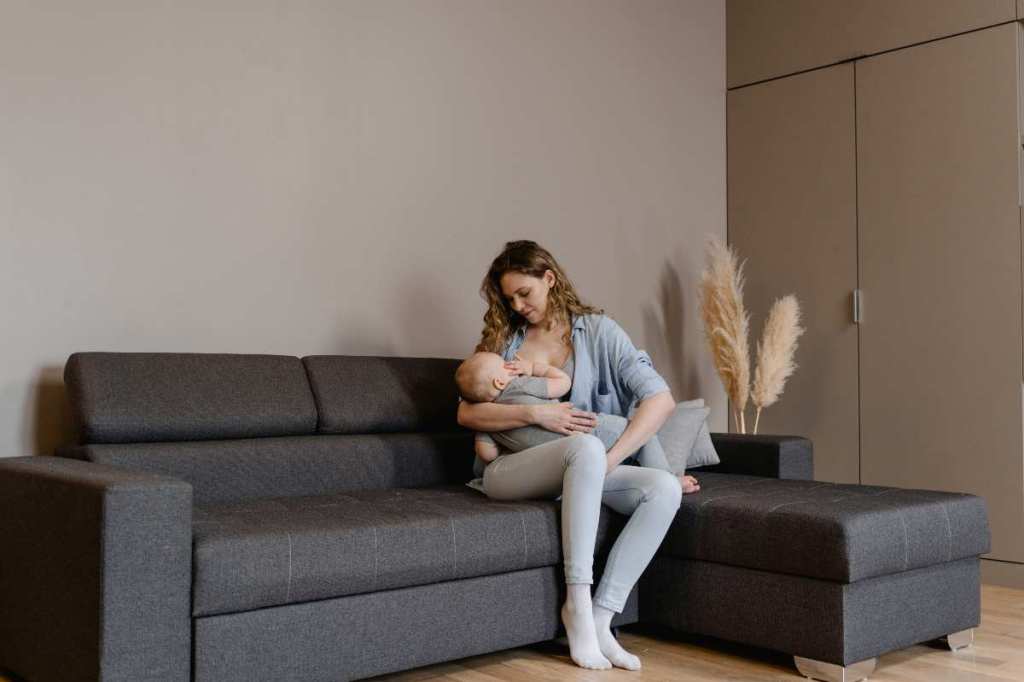 a woman breastfeeding on a leather sectional