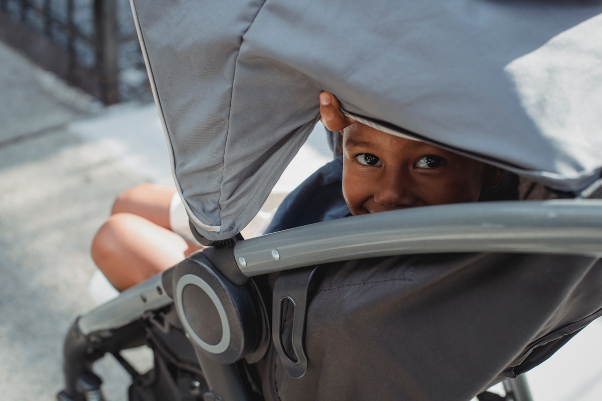 Child peeking out from the canopy of a stroller