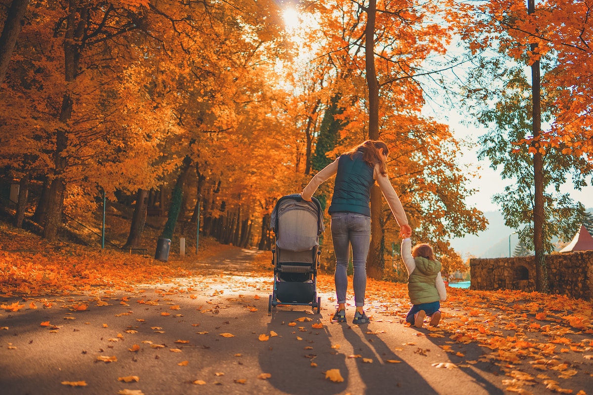 Mom pushing stroller with one hand while holding child's hand