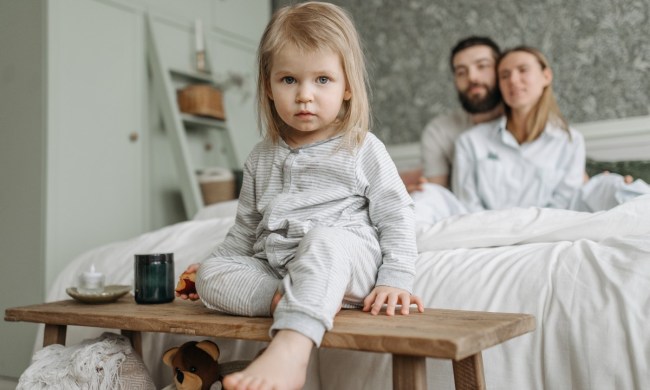 Small child sitting on the edge of a bed