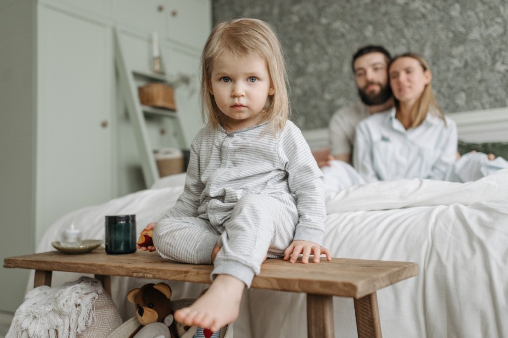 Small child sitting on the edge of a bed