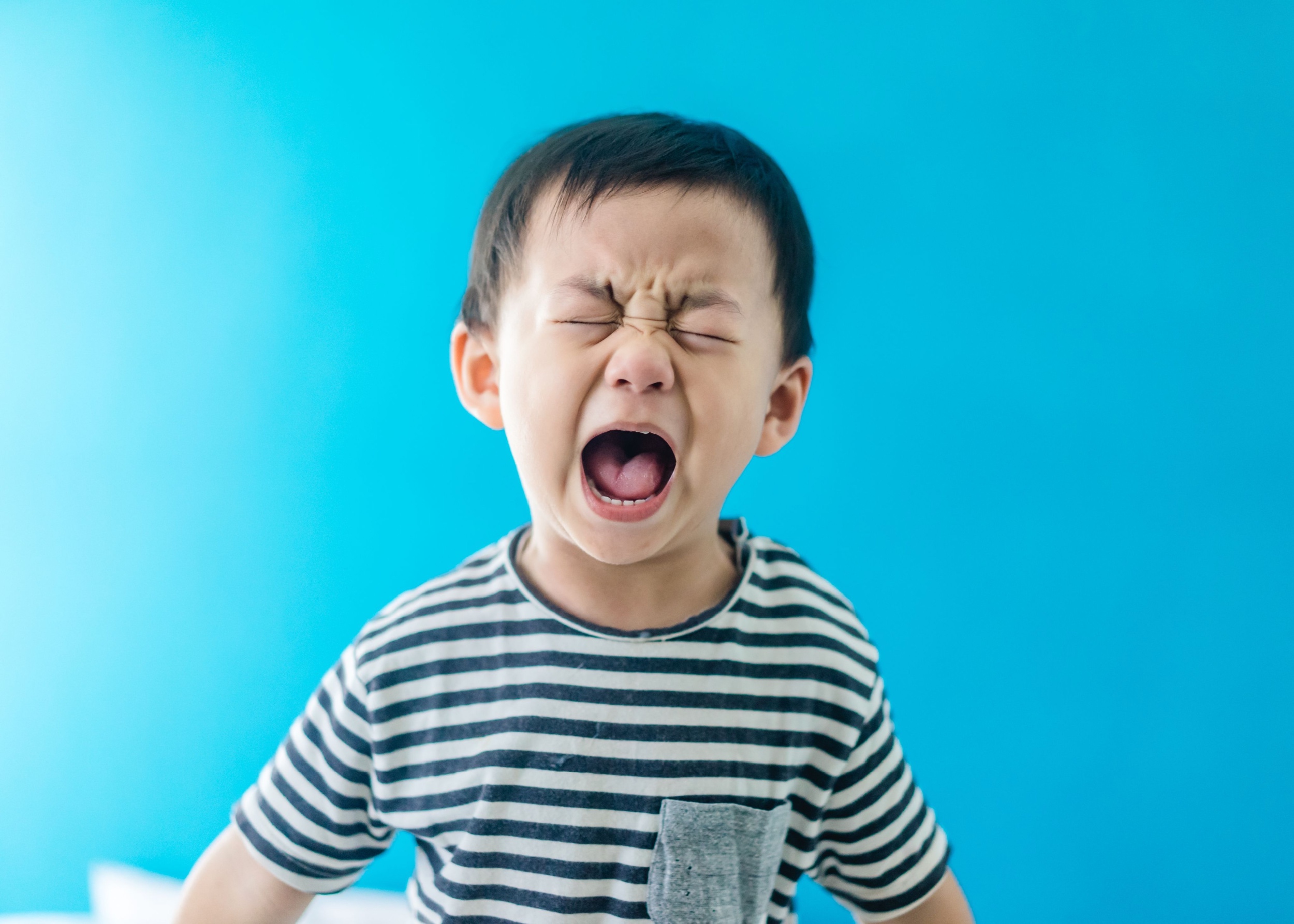 A little boy screaming with his eyes closed.