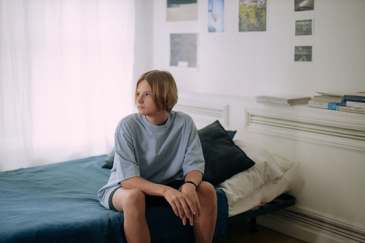 Teen boy sitting on a bed