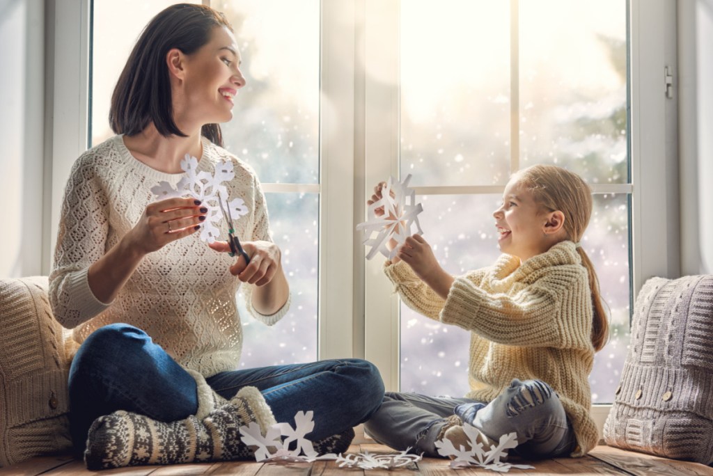Mother and child having fun making paper snowflakes