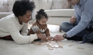 Two parents playing with blocks with a child.