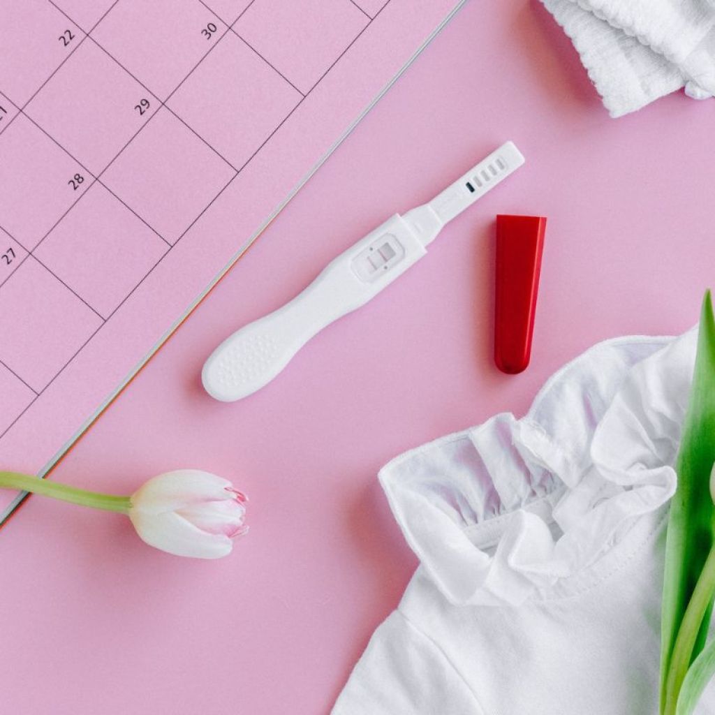 A pregnancy test with flowers and a calendar