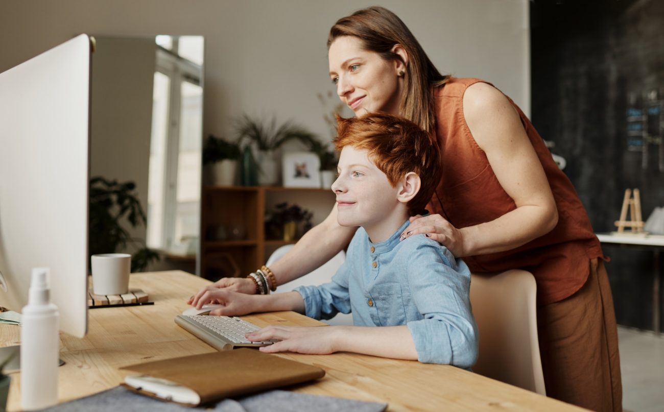 A mother helping her child with work on the computer.