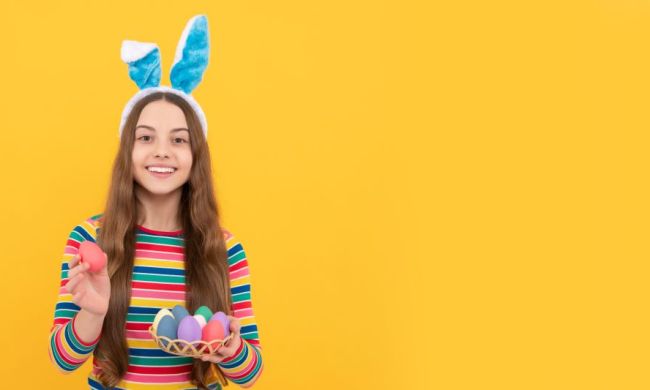 Teen girls holding basket of Easter eggs wearing bunny ears