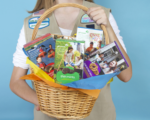 Girl Scout holding various Girl Scout cookies
