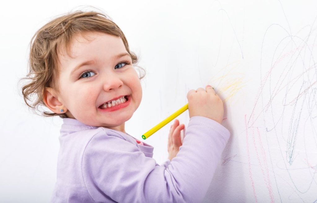 smiling child drawing on the wall