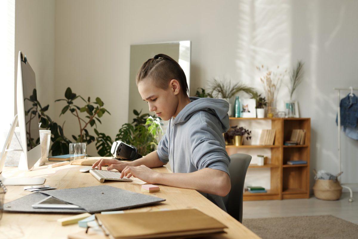A child sitting at the desk typing away.