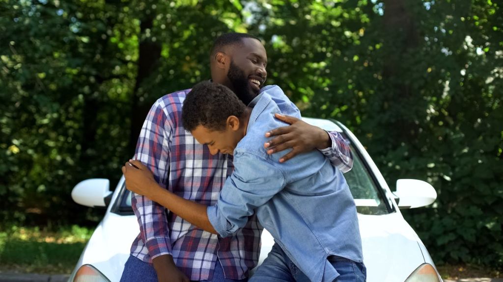 Excited son hugs dad after getting a car
