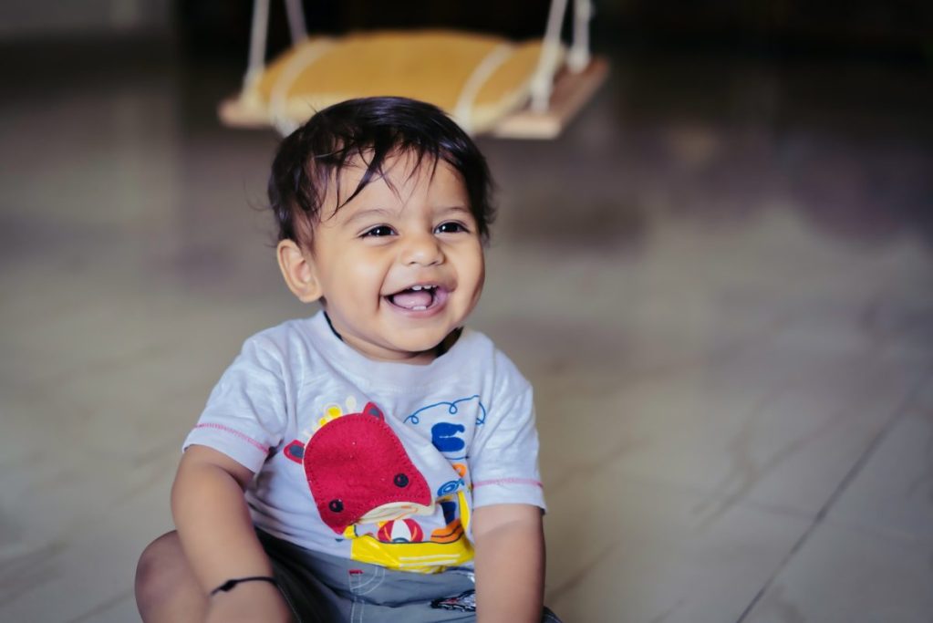 A baby smiling while sitting up.