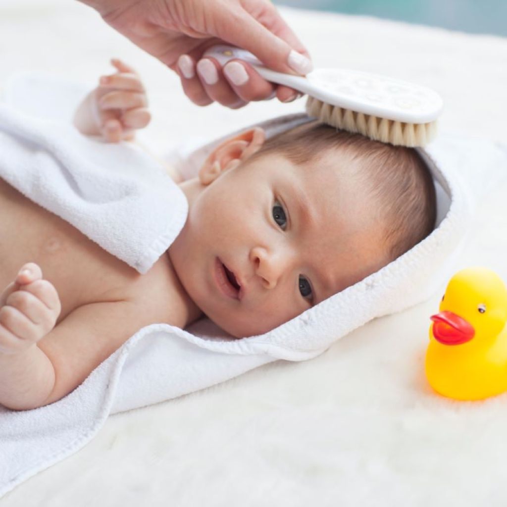 Parent brushing a baby's hair