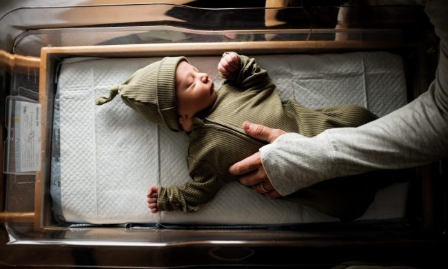 A newborn baby in their bassinet.
