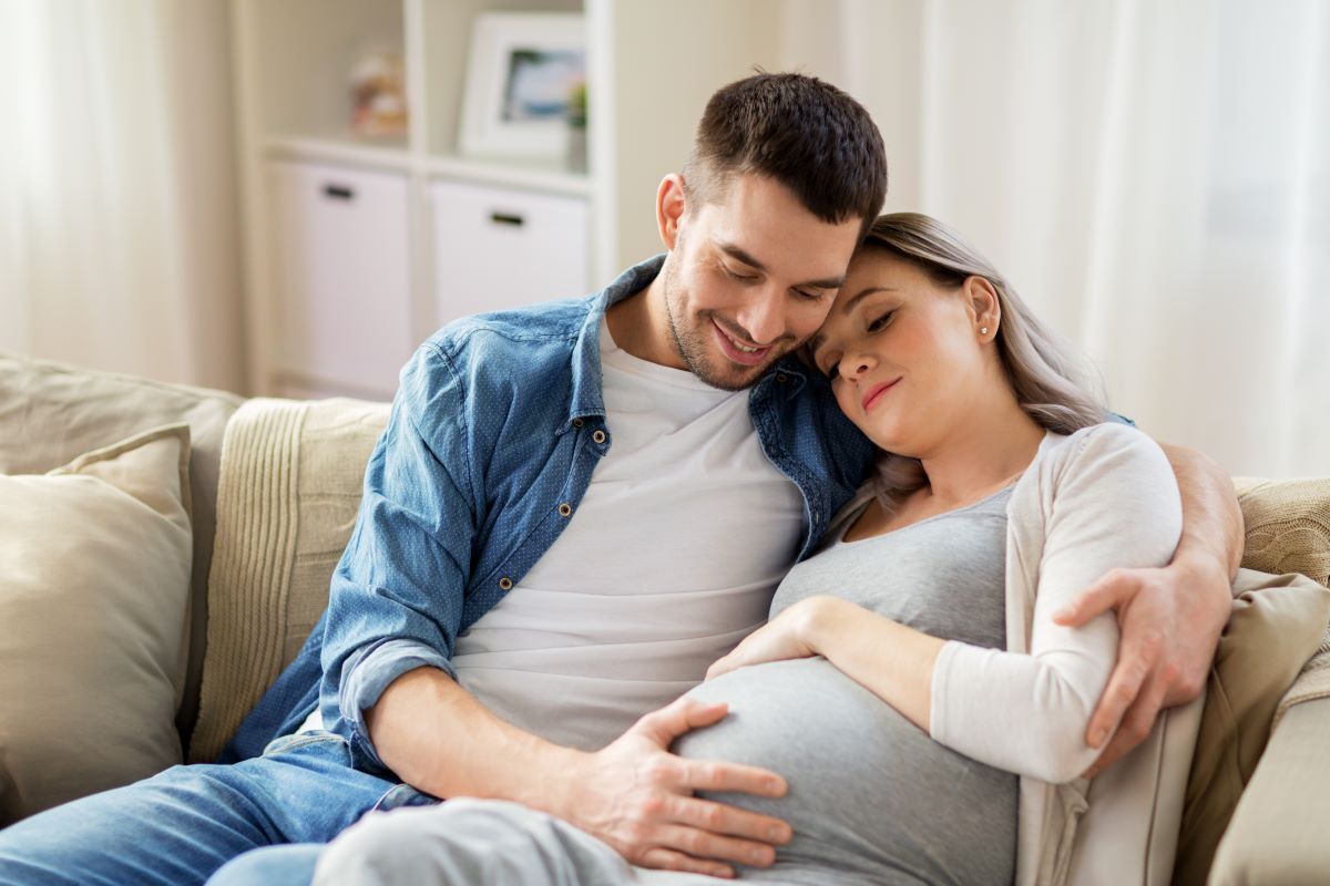 Pregnant couple cuddling.