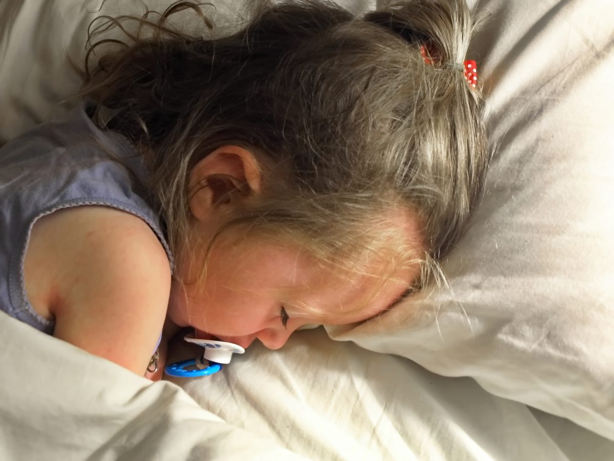 A toddler sleeping in the bed.