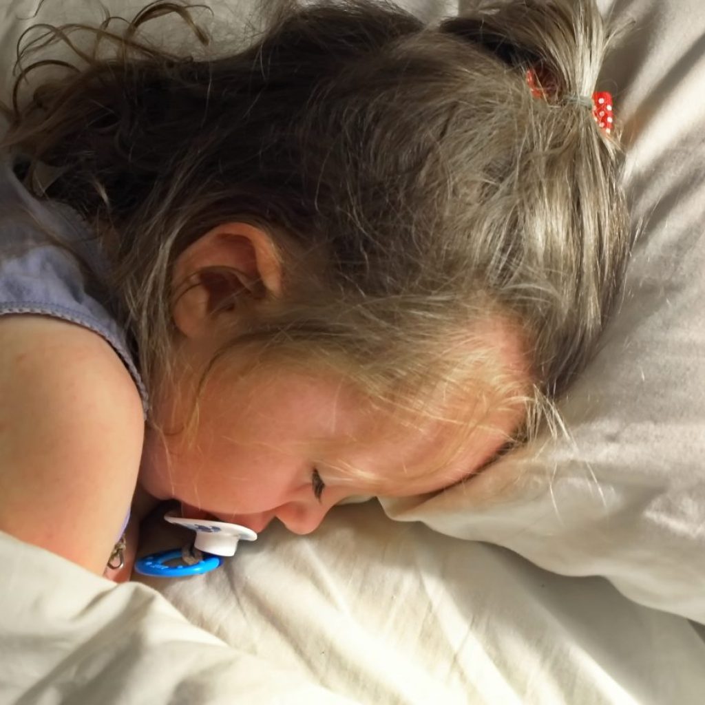 A toddler sleeping in the bed.