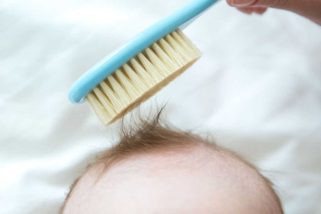 Mom brushing small amount of hair on a toddler