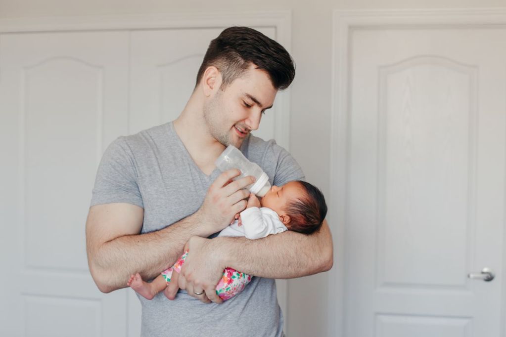 Dad feeding his newborn with a bottle.