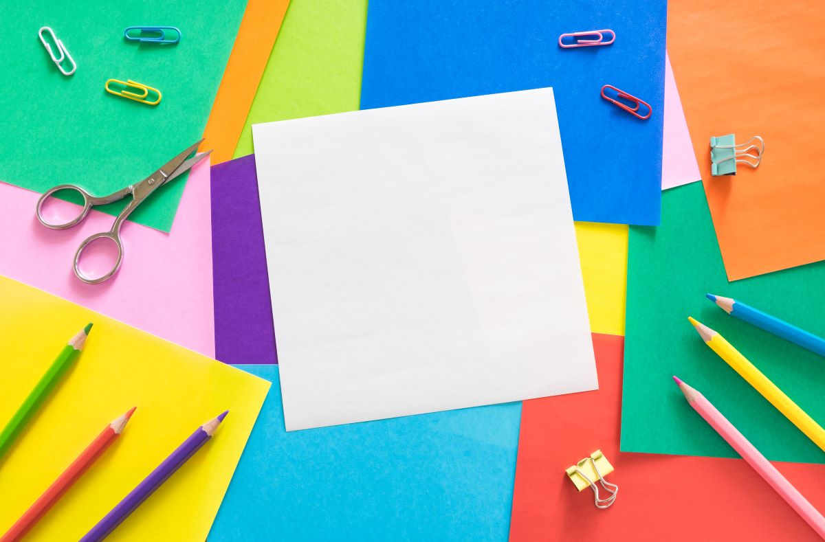 Colorful construction paper with pencils and paperclips