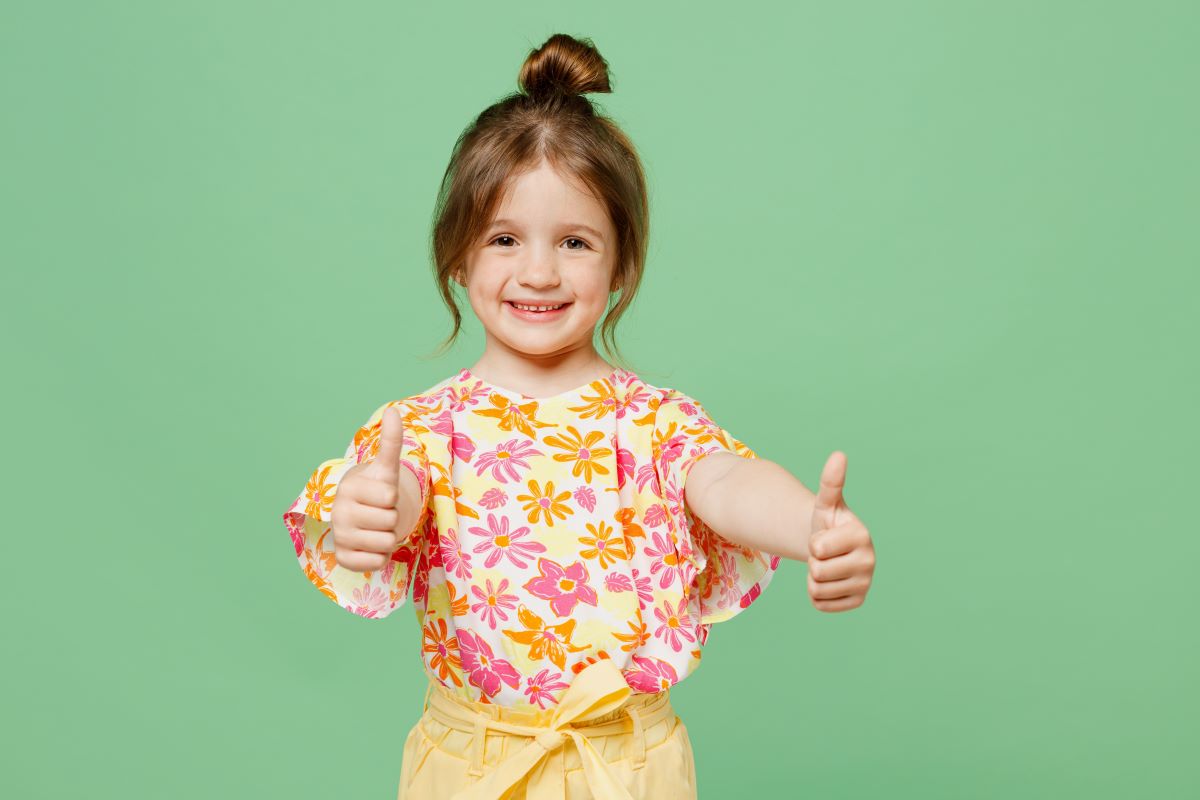 cute little girls smiling with her thumbs up