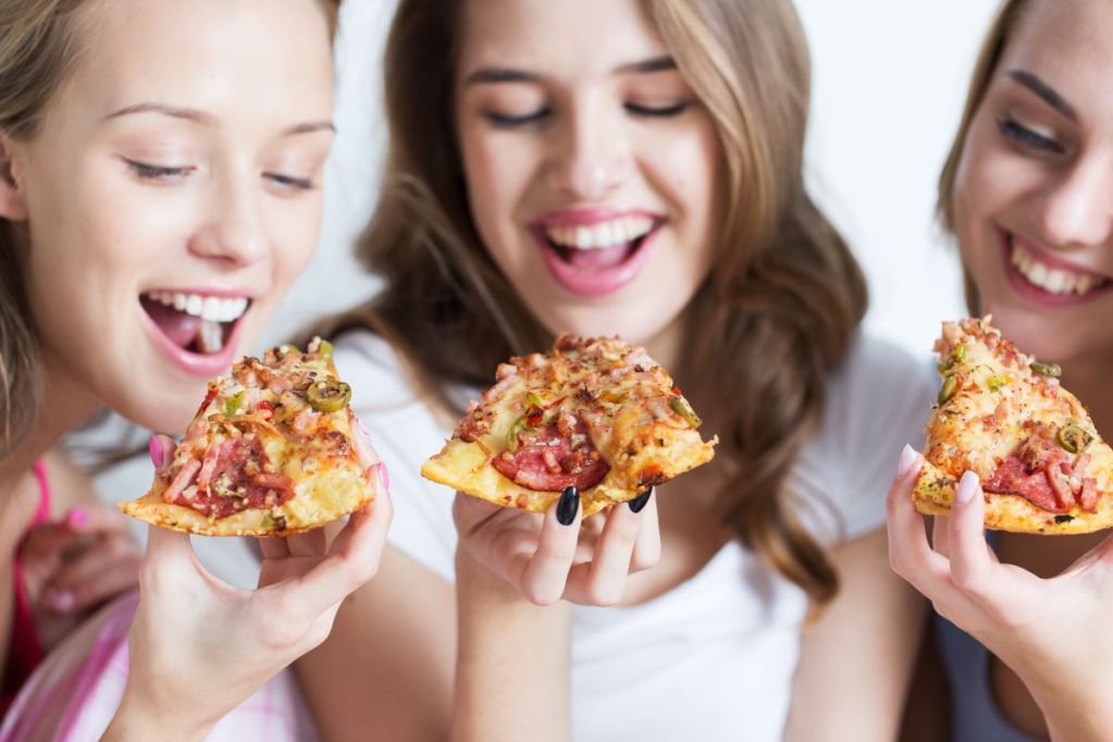 Three teen girls enjoying homemade pizza at a party