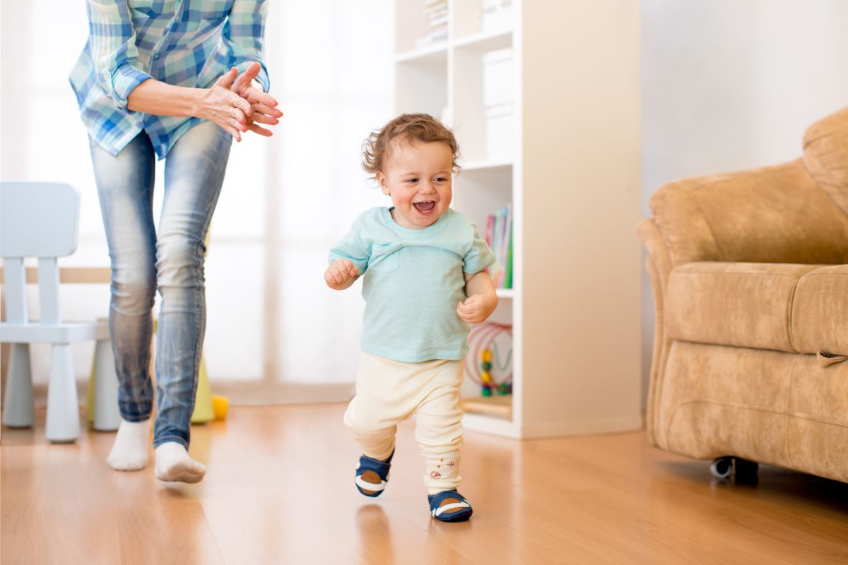 happy toddler boy running with mom following behind
