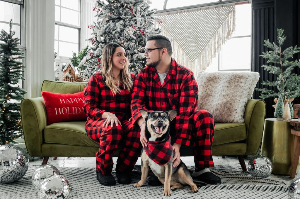 A couple and their dog taking a matching Christmas photo.