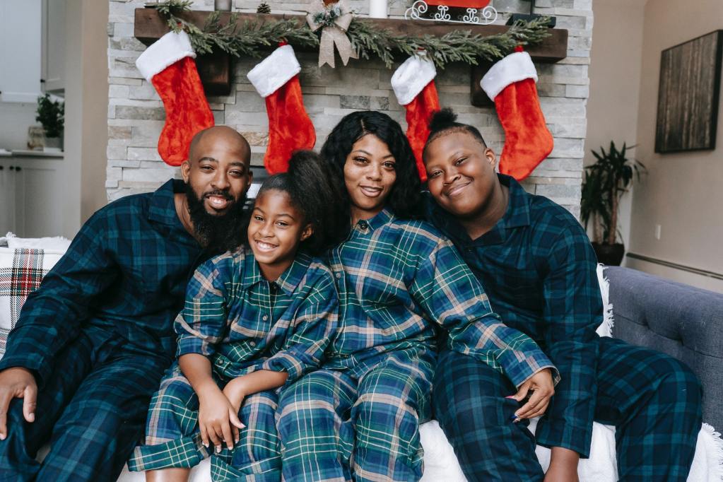 A family in pajamas in front of Christmas decorations.