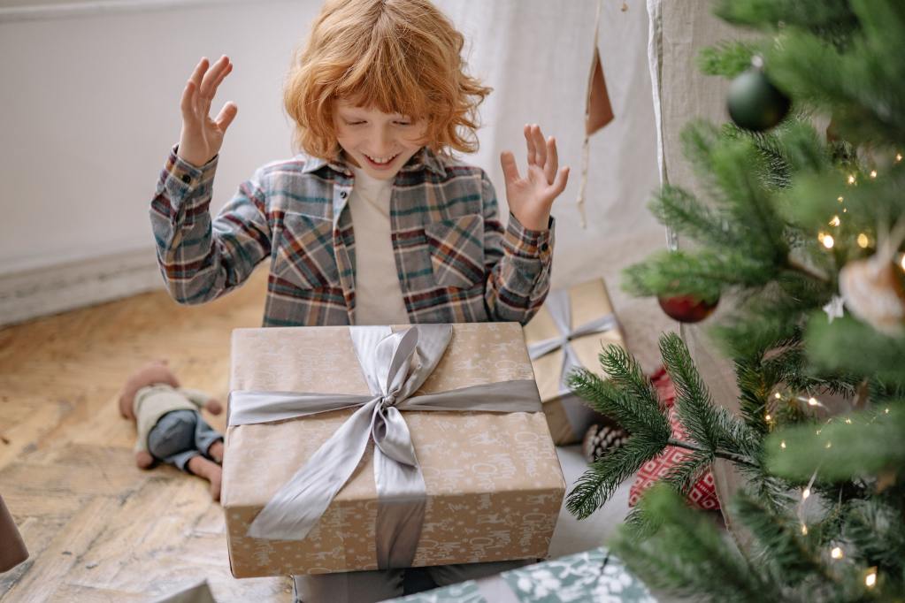 A happy child about to open a Christmas present.