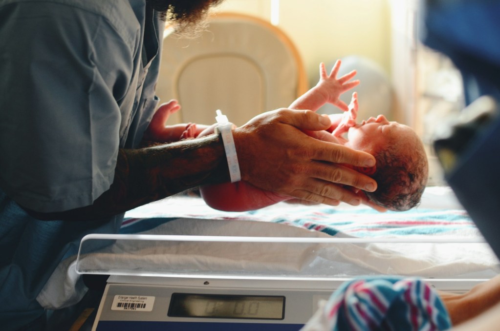 A parent holding a newborn baby in the hospital room.