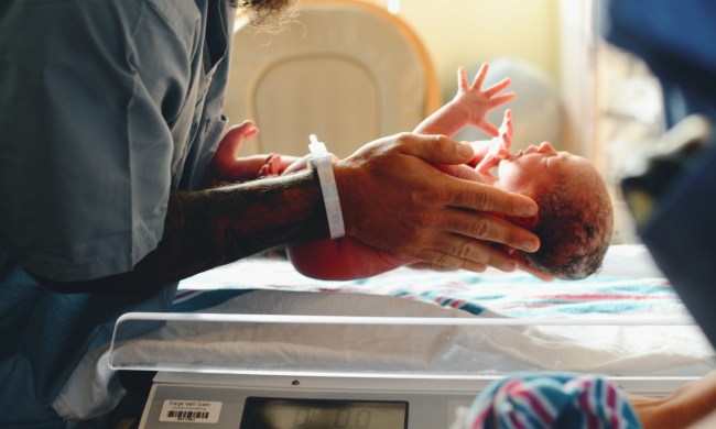 A parent holding a newborn baby in the hospital room