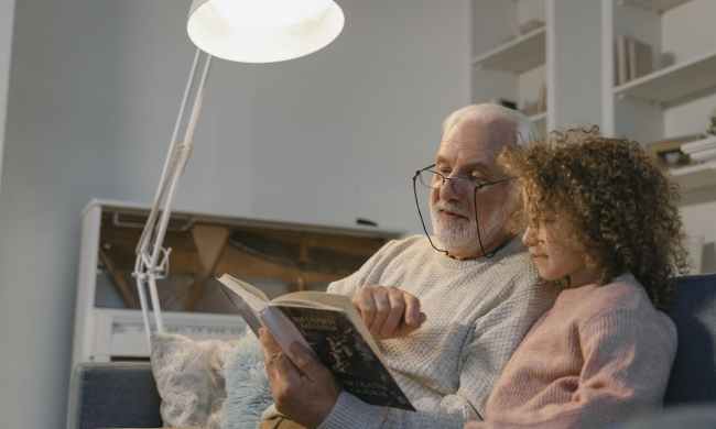 Grandfather reading a story to his young granddaughter
