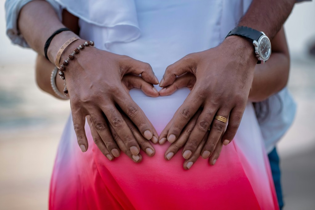 A couple with their hands over pregnant belly.